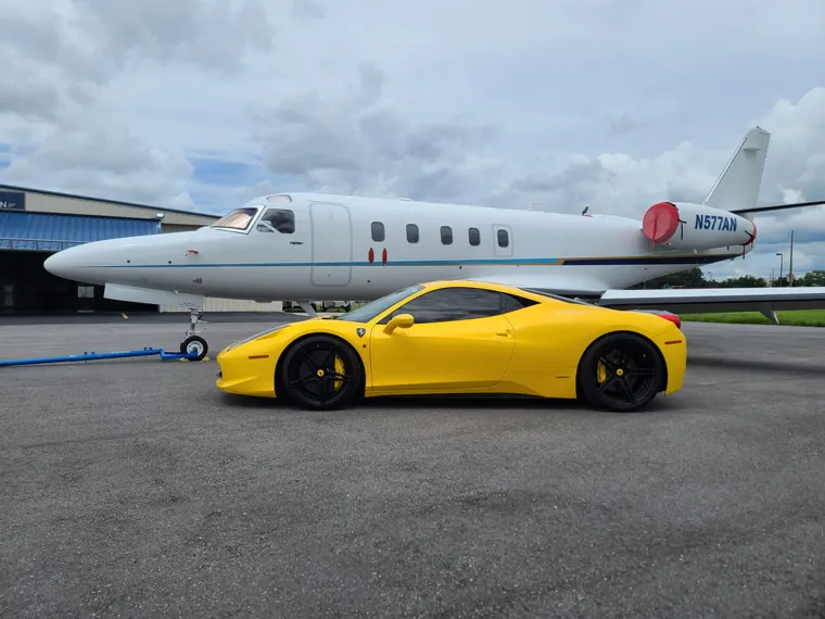 Yellow Ferrari beside a private jet