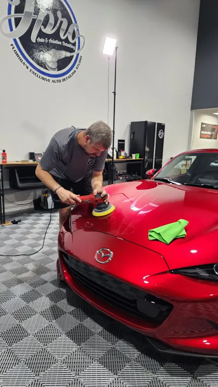 Hand polishing a red sports car